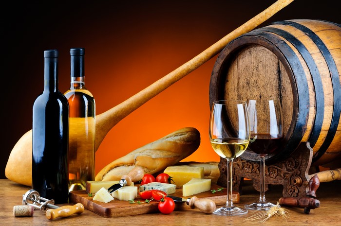 Wine bottles, glasses, cheese, bread, and barrel