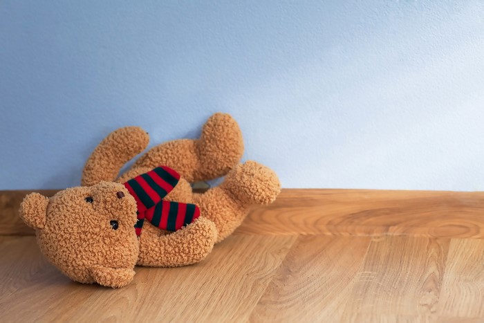 Teddy bear with scarf on wooden floor