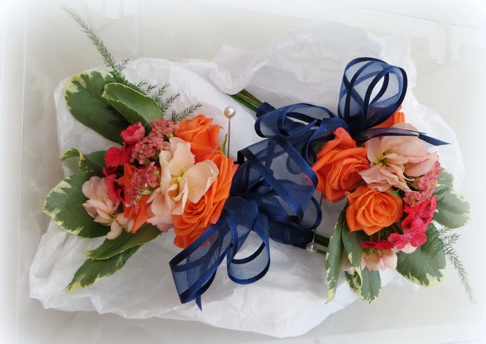 Two floral arrangements with orange roses and navy bows