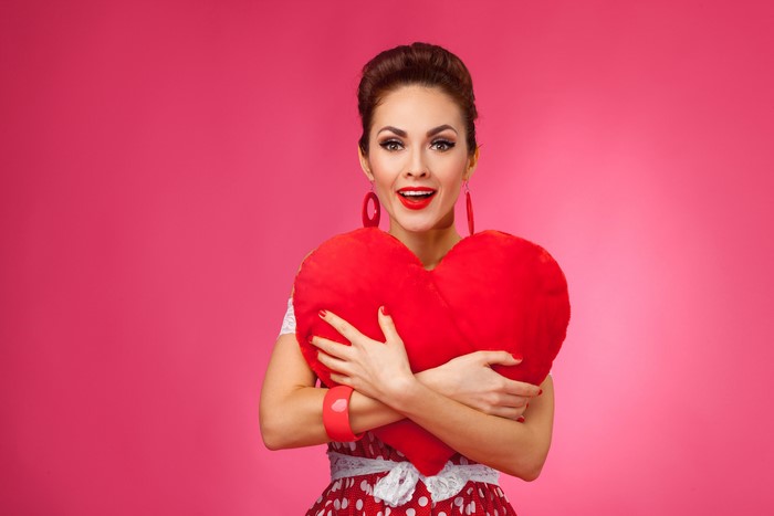 Woman holding a red heart pillow