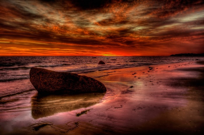 Sunset over the sea with stones on the coast