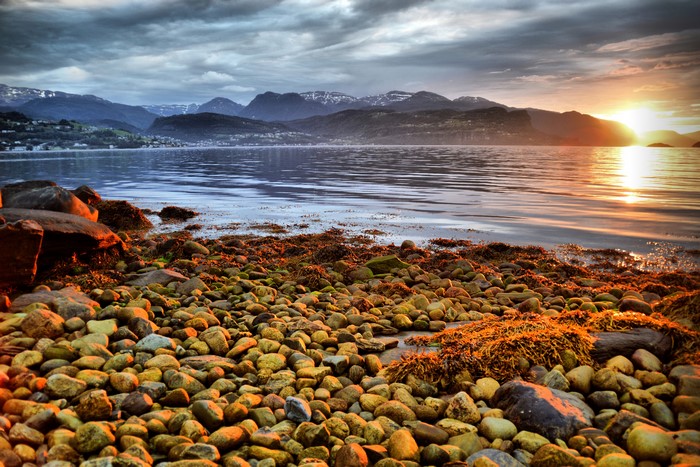 Sunset over Hardangerfjorden, Norway with rocky shore