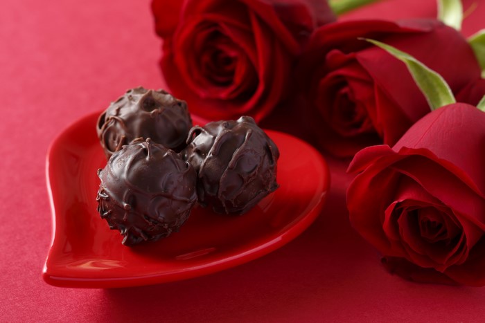 Chocolate truffles on a heart-shaped plate with red roses