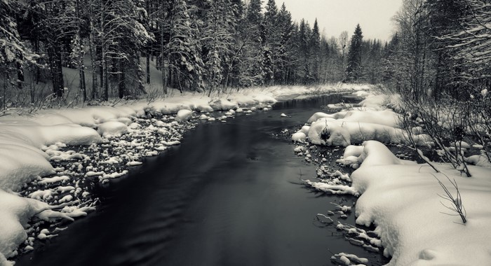 Winter river flowing through a snow-covered forest