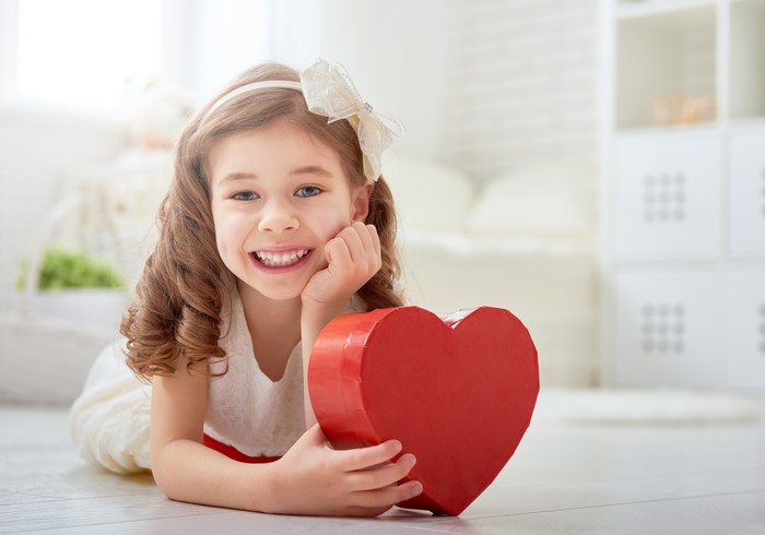 Little girl with brown hair holding a red heart