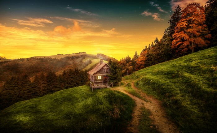 Cabin on a grassy hill at sunset