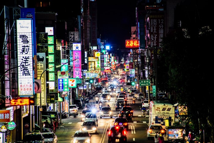 Night street with neon signs and traffic