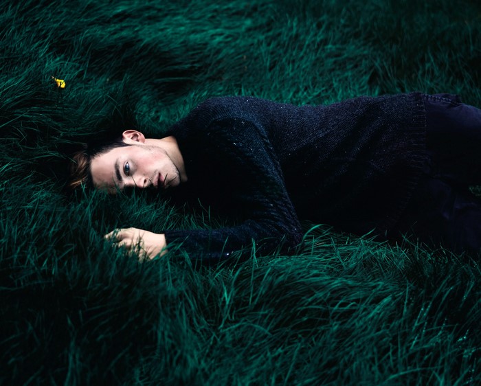 Man lying in dark green grass