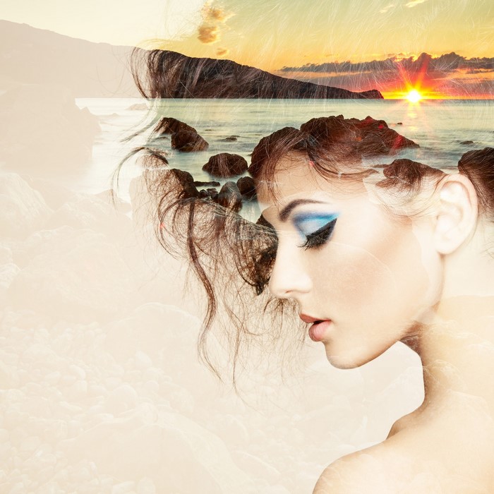 Double exposure of a woman's face and a sunset over the ocean