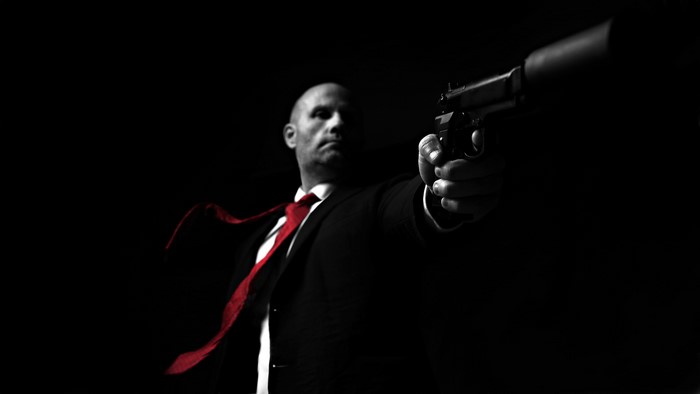 Man in Suit with Red Tie Holding Pistol