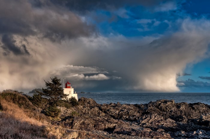 Lighthouse on rocky coast under dramatic clouds in Ucluelet, Canada