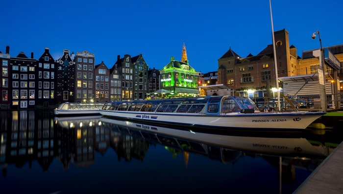 Amsterdam canal at night with riverboats and houses