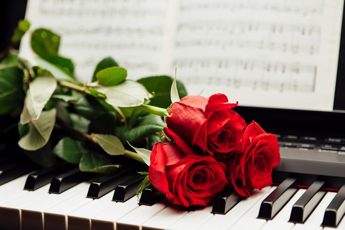 Three Red Roses on Piano with Sheet Music