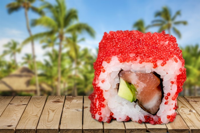 Sushi with caviar on a wooden table with palm trees