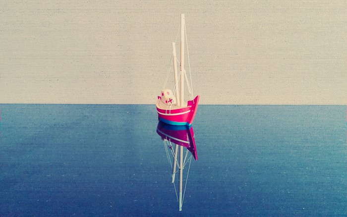 Toy sailboat on reflective surface