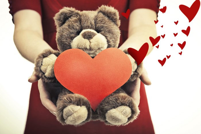 Teddy bear holding a red heart with hearts flying