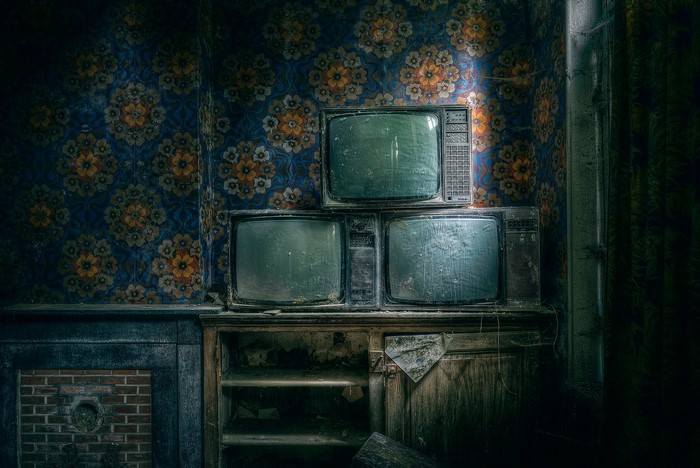 Three old TVs stacked in a room