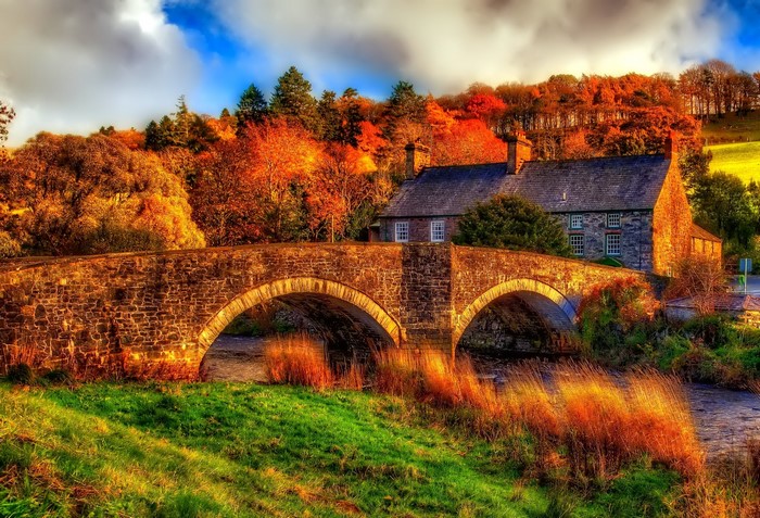 Stone bridge over a river in autumn with a house
