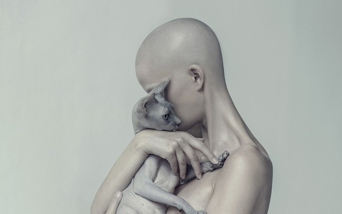 Bald woman holding a Sphynx cat