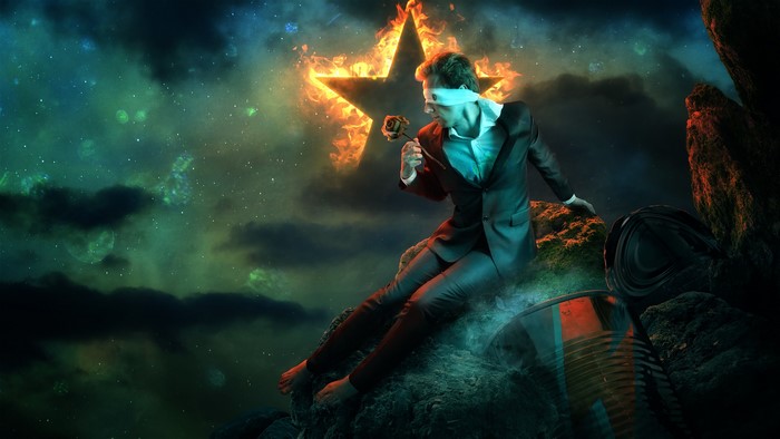 Man in suit blindfolded with a rose in front of a burning star