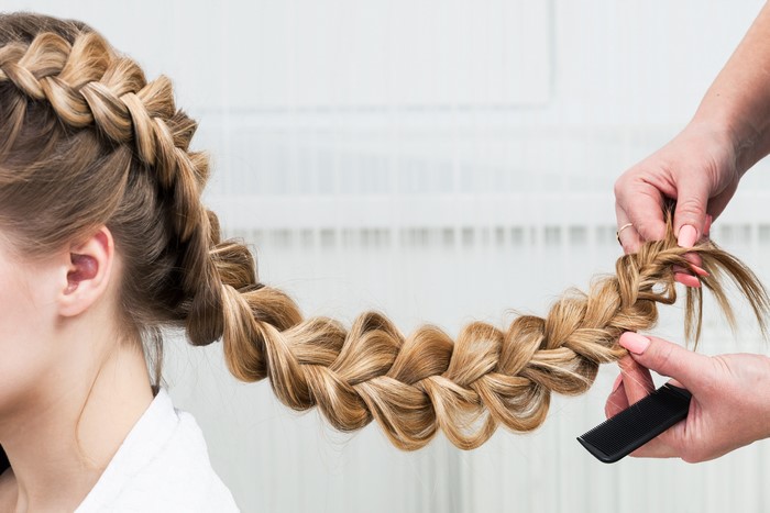 Close-up of a woman's braided hair with hands styling it