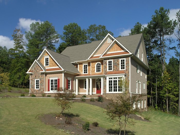 Large house with stone and wood siding on a grassy hill