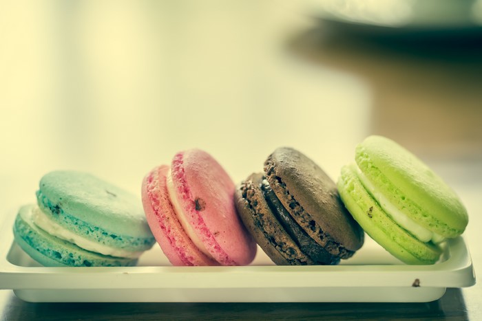 Four colorful macarons on a white plate