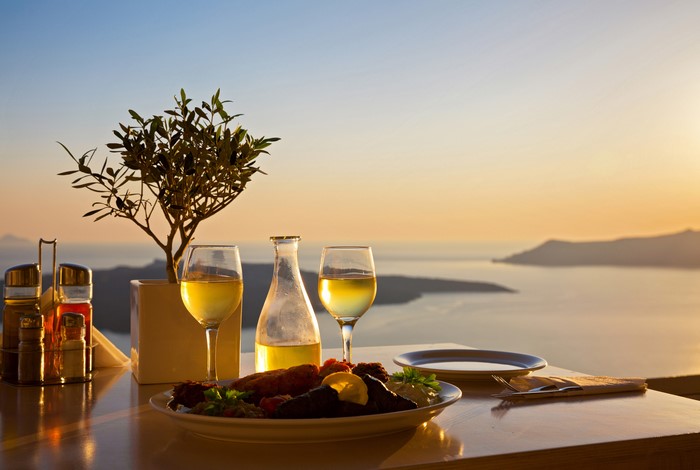 Table setting with wine and food overlooking the sea at sunset