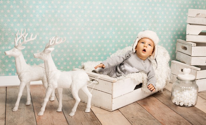 Infant in a sleigh with deer and winter hat
