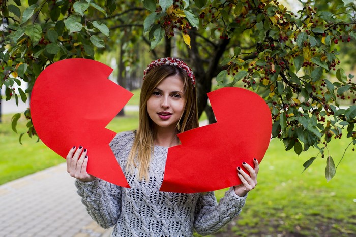 Woman holding a broken red heart