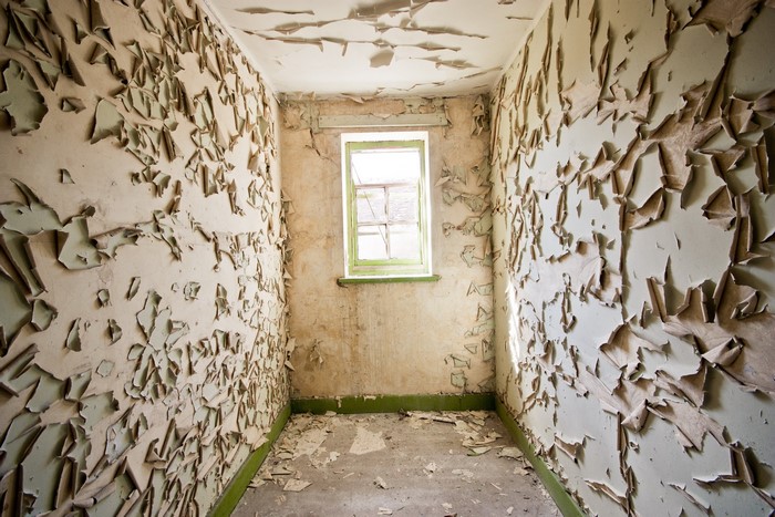 Interior room with peeling paint and a window