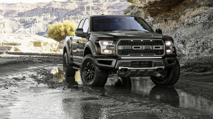 Black Ford F-150 Raptor driving through water