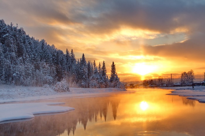 Winter sunrise over a snowy forest and river