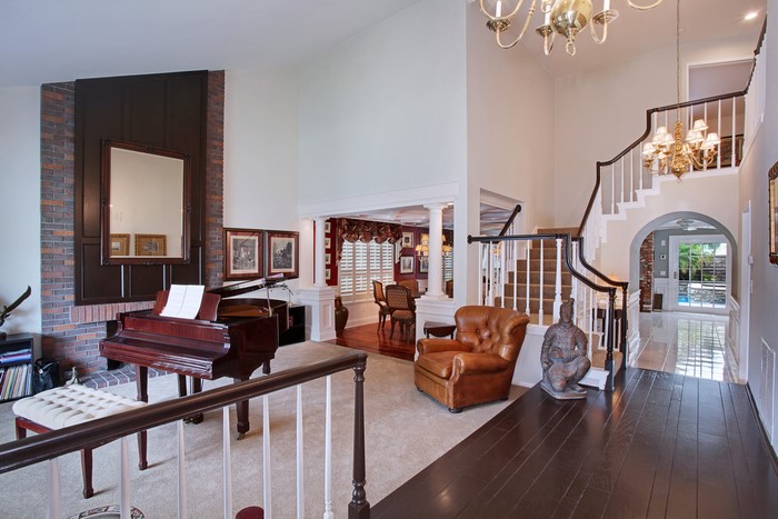 Grand piano and armchair in a living room with stairs
