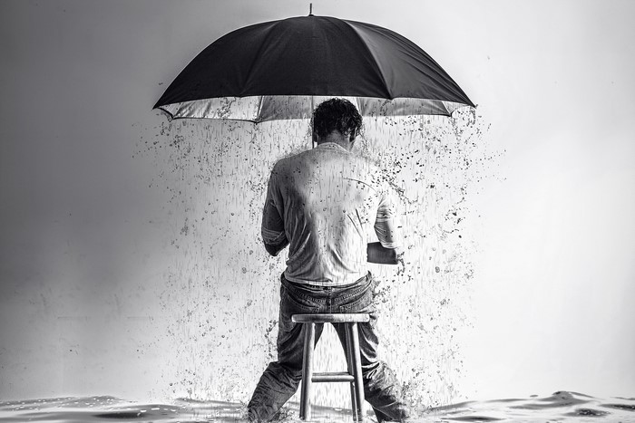 Man sitting under an umbrella in the rain
