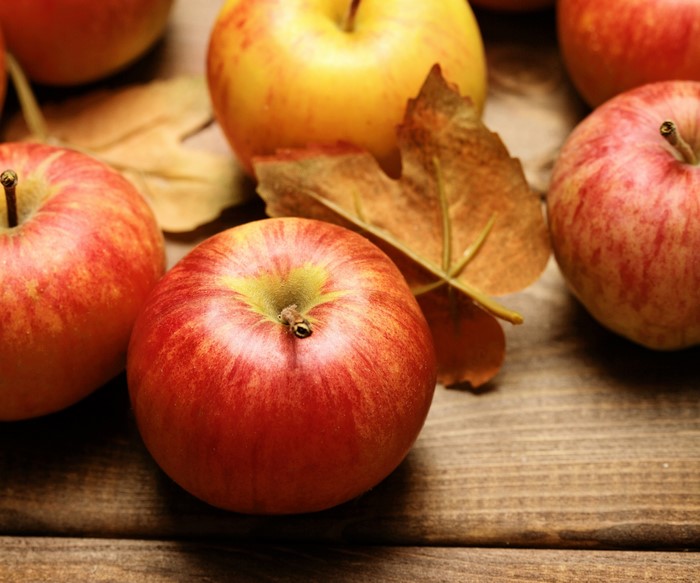 Apples and autumn leaves on a wooden surface