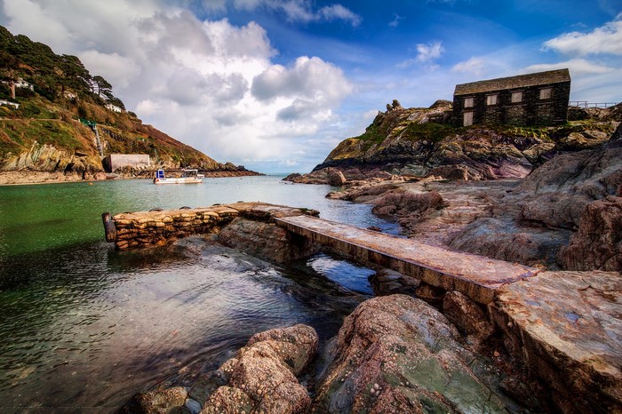 Coastal cove with a boat and stone building in Cornwall, England