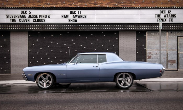 Blue 1960s Chevrolet Impala parked in front of a theater