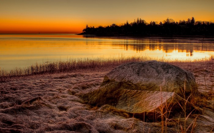 Sunrise over a calm lake with a rocky shore