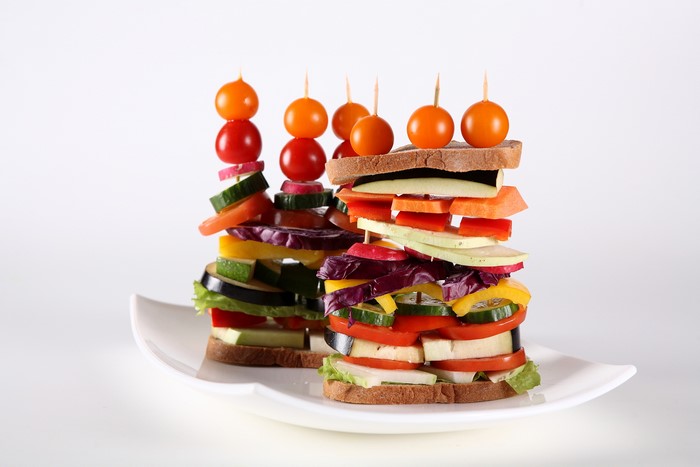 Tall vegetable sandwiches with cherry tomatoes on top