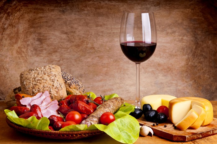 Still-life with wine, cheese, bread, and sausage