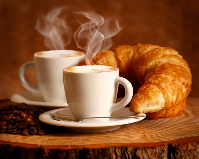 Two cups of coffee and a croissant