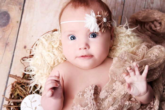 Baby with flower headband in a basket