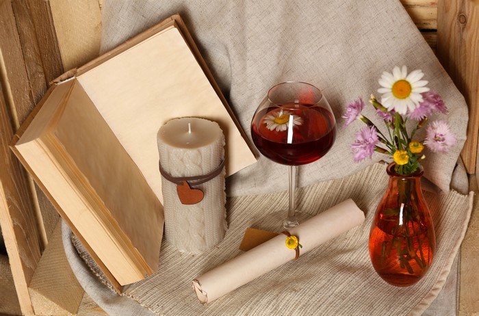Candle, wine, and flowers on a wooden background