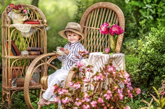 Boy in a hat having tea in a garden
