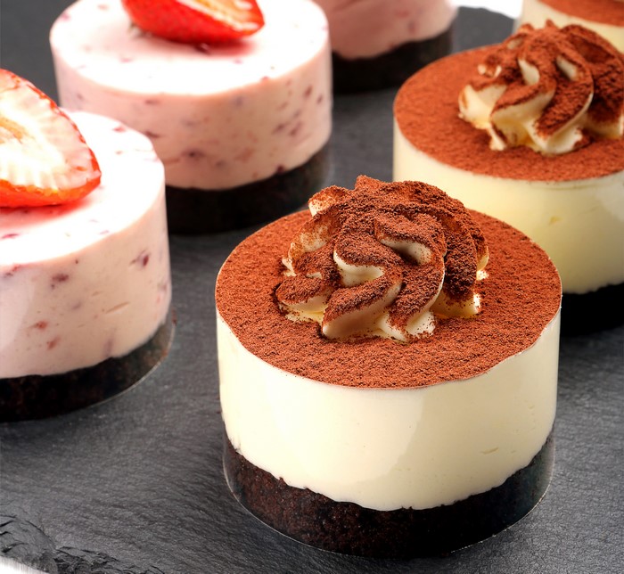 Four small cakes with strawberries and cocoa powder