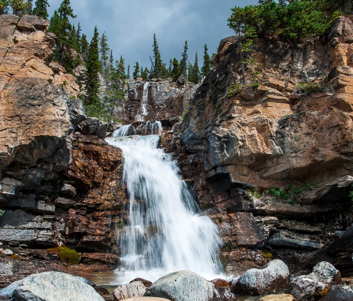 Waterfall cascading over rocky cliffs with pine trees