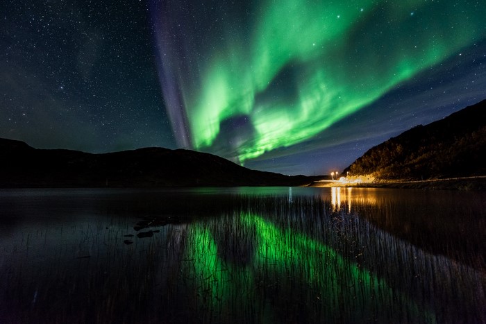 Aurora Borealis over a lake and mountains at night