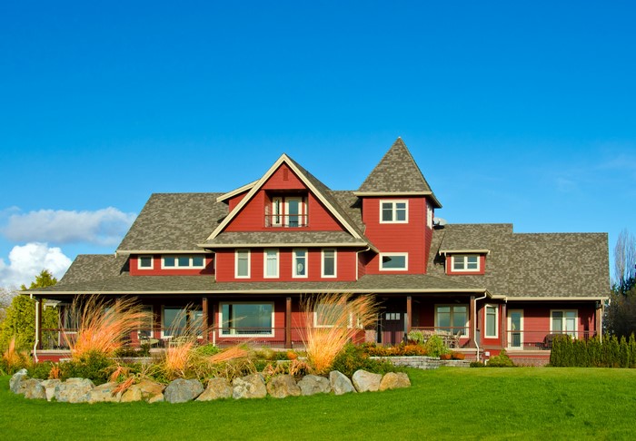 Red house with a large lawn and blue sky
