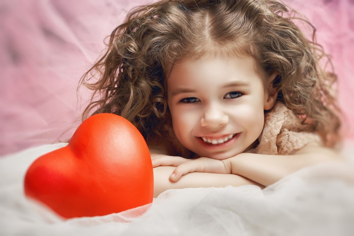 Little girl with brown hair and a red heart